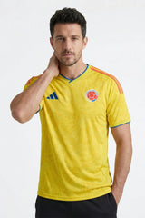 Man wearing a yellow sports jersey with a logo on a white background