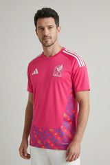 Man wearing a pink sports jersey with Adidas logo on a gray background