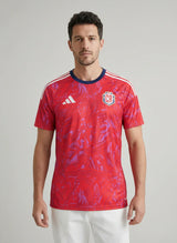 Man wearing a red sports jersey with Adidas logo on a gray background