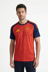 Man wearing a red and navy sports jersey with a logo on a white background