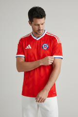 Person wearing a red sports jersey with a logo on a gray background